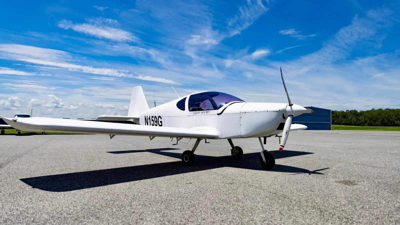Direct Fly Alto N159G, a white two-seat low-wing trainer, parked on the ramp under a blue sky